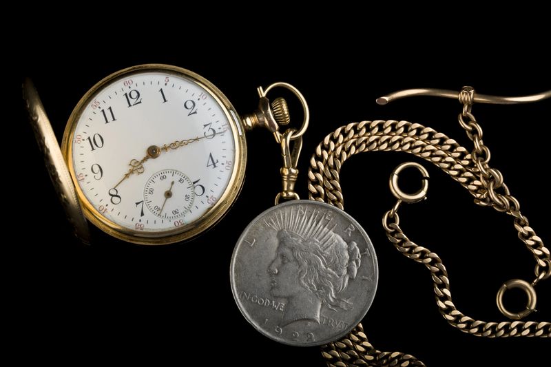 Peace silver dollar beside a gold pocket watch from a Philadelphia family estate